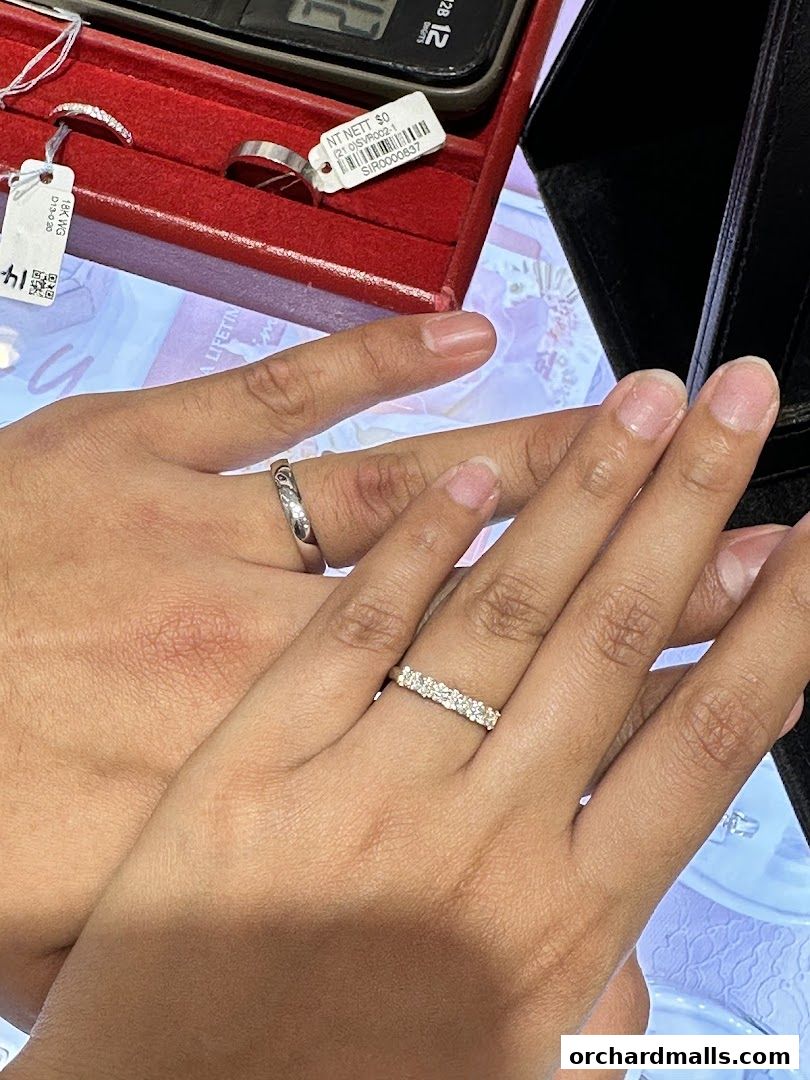 Close-up of two hands wearing wedding bands, showcasing diamond rings.