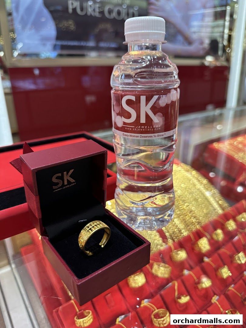 A gold ring in a red box next to a bottle of water at SK Jewellery.