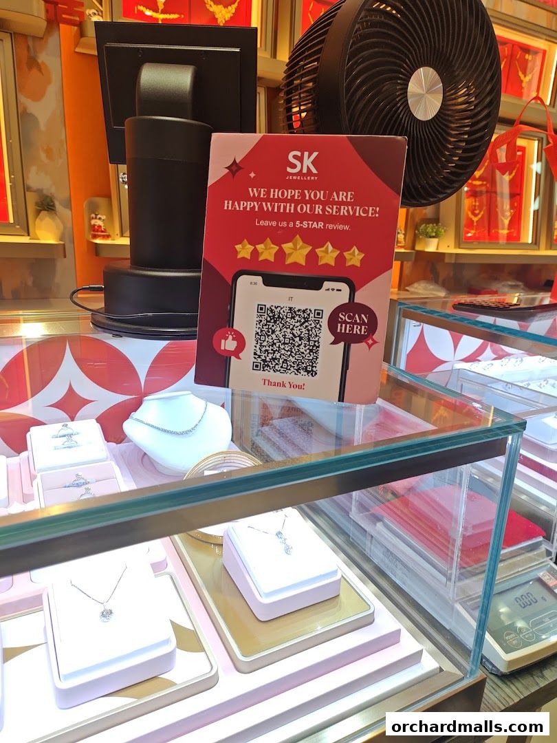 A jewelry display case with necklaces and rings, and a sign asking for a 5-star review.