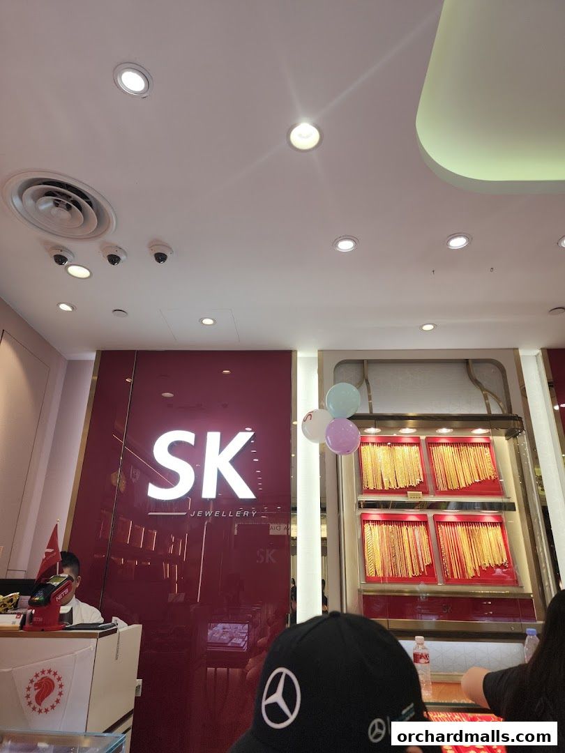 SK Jewellery shop front with displays of gold necklaces and a cashier counter.