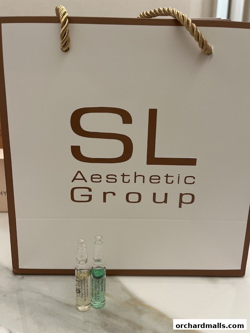Two ampoules of aesthetic products in front of a branded shopping bag.