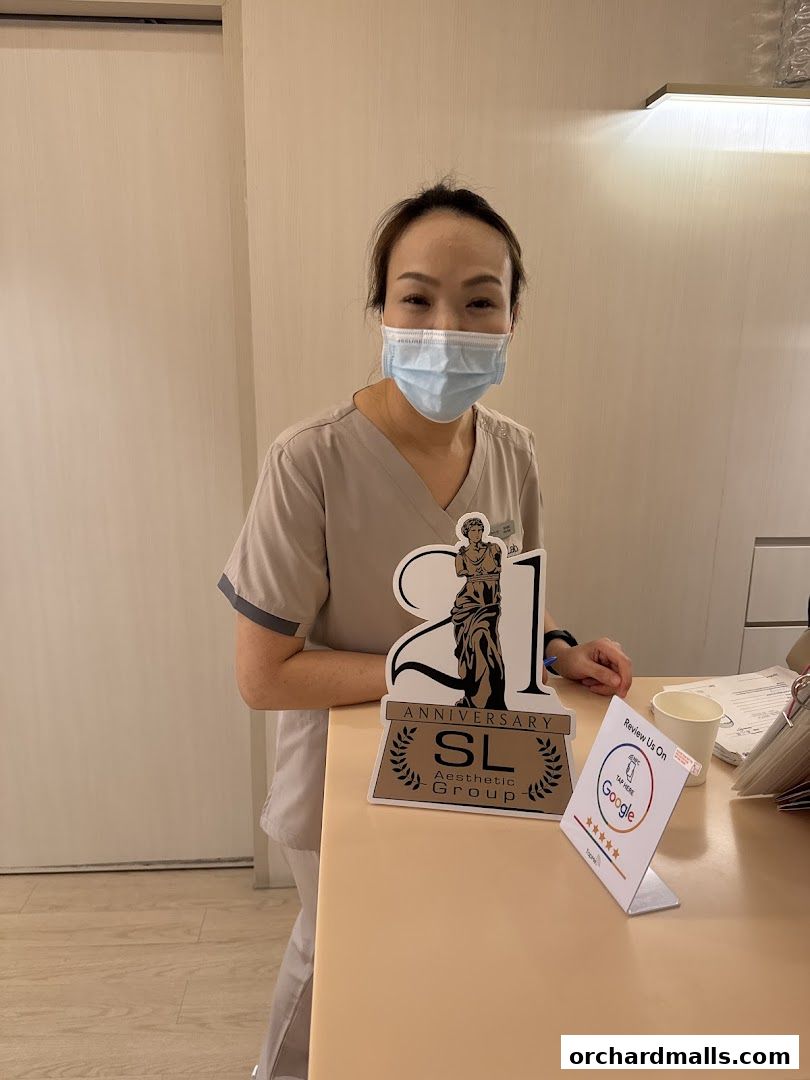A masked staff member stands behind a counter with anniversary and review signage.