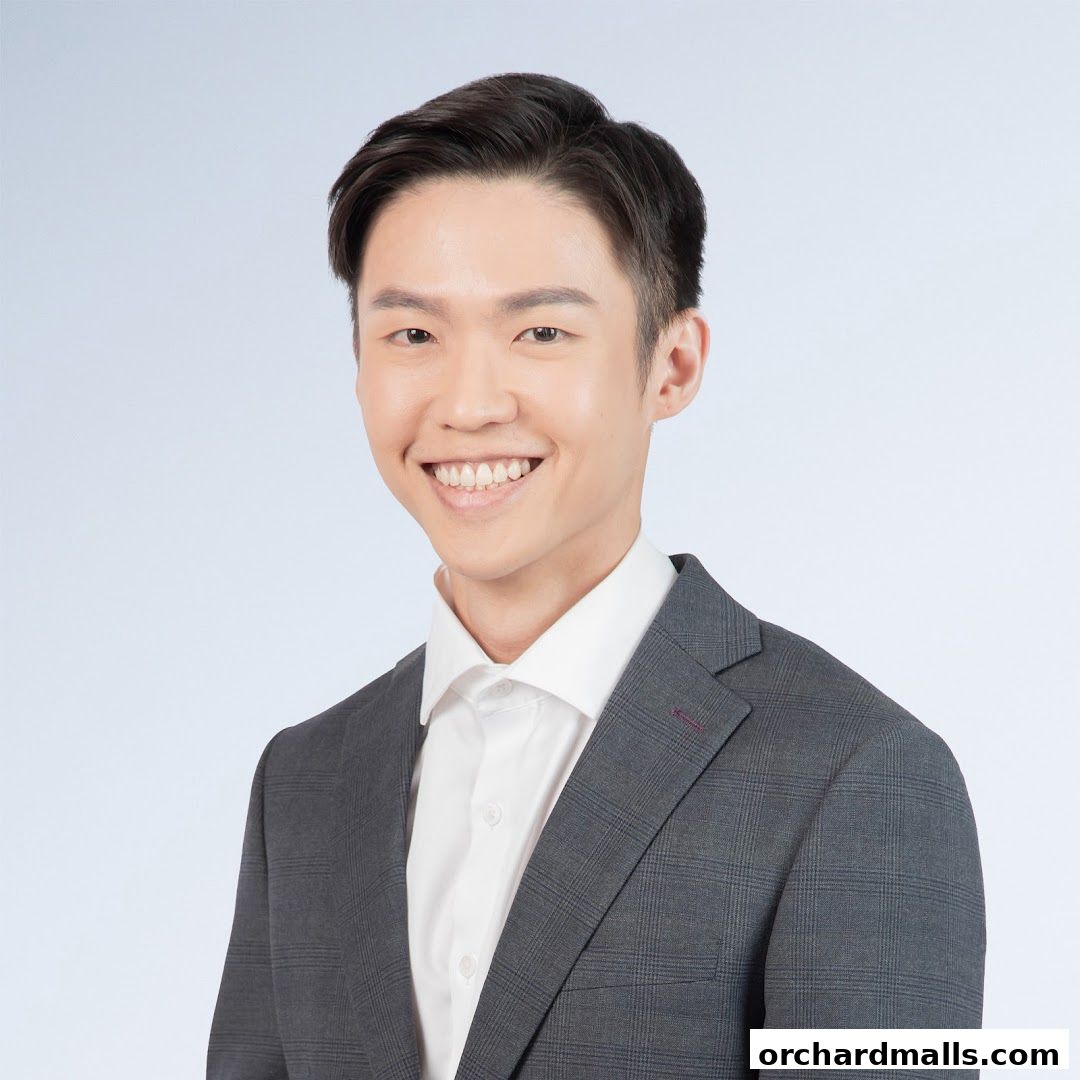 A smiling young man in a grey suit and white shirt.