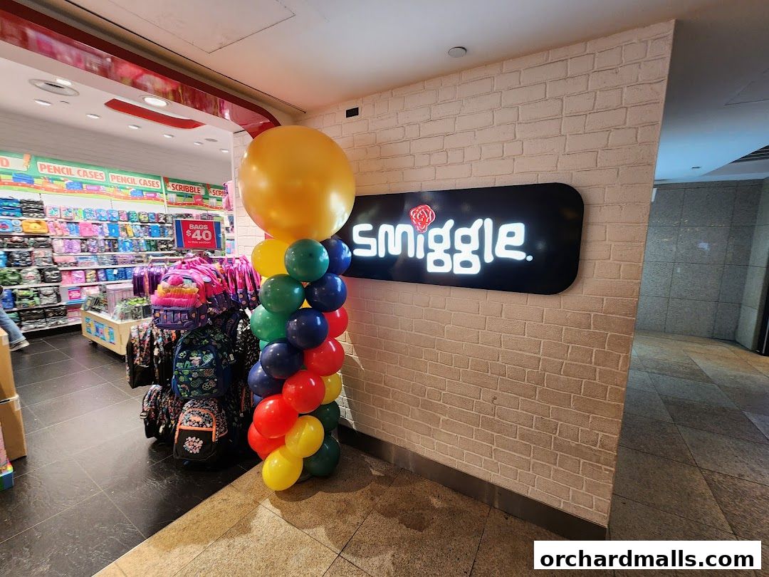 Smiggle store entrance with colorful balloons and displays of bags and stationery.