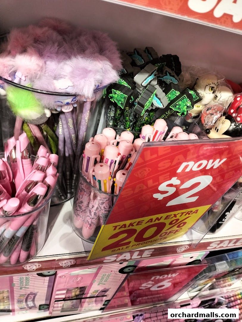A display of colorful pens, erasers, and stationery items with sale signs.