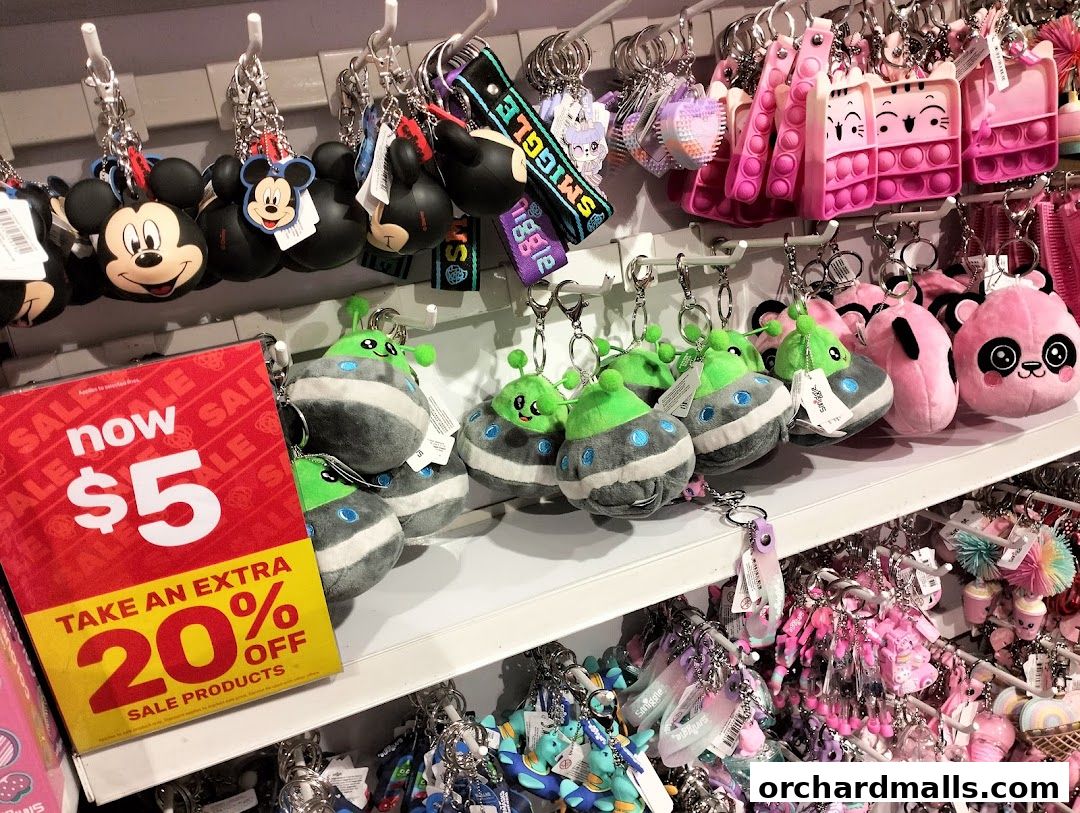 A display of colorful Smiggle keychains and plush toys, with a sale sign.