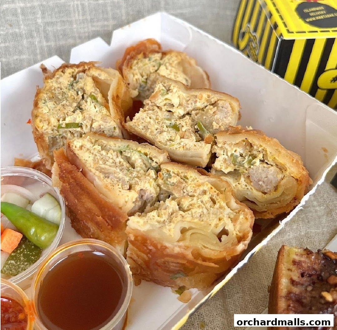 A close-up of savory martabak slices with a side of pickles and dipping sauce.