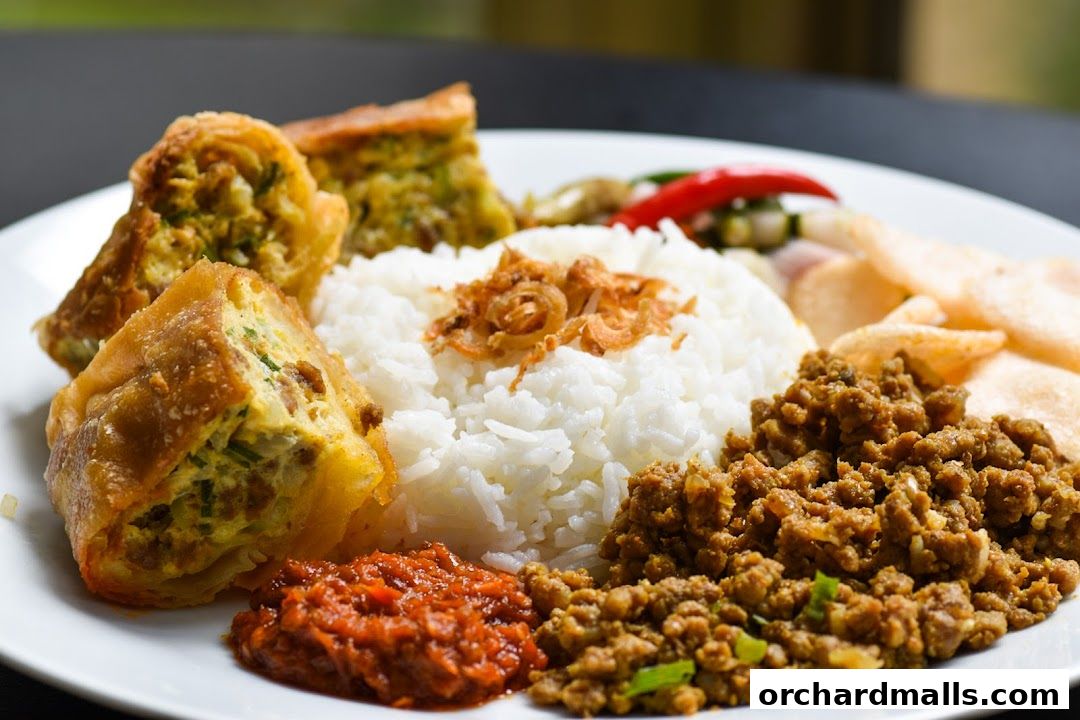 A plate of Indonesian food with rice, fried tofu, minced meat, chili paste, and crackers.