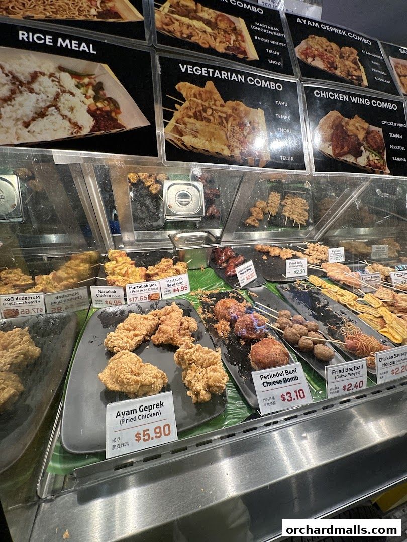 A display of various Indonesian fried snacks and meals with prices.