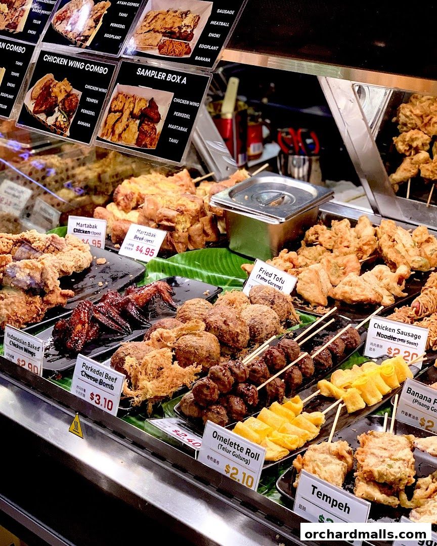 A display of various fried Indonesian snacks and dishes, including chicken wings, tofu, and tempeh.