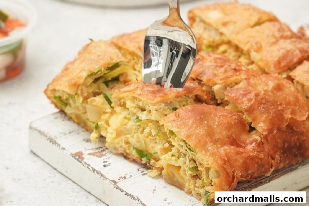 A close-up shot of a savory martabak, cut into squares, with a fork inserted.