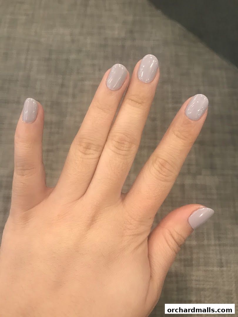 A hand with neatly manicured nails painted in a soft grey polish.