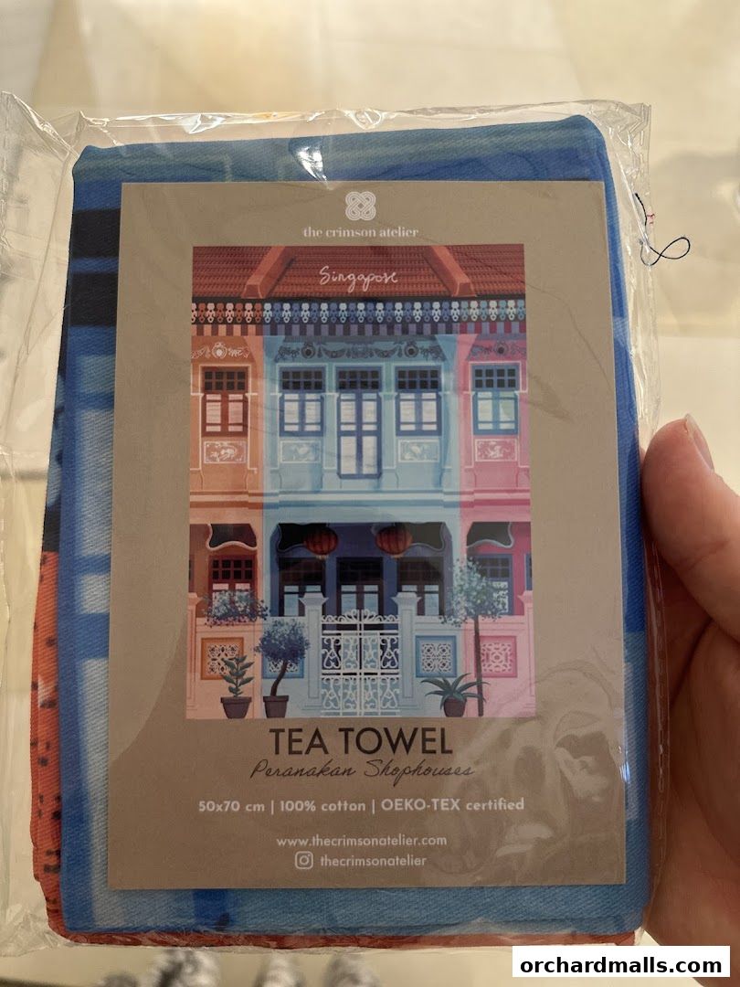 A tea towel featuring a colorful illustration of Peranakan shophouses in Singapore.