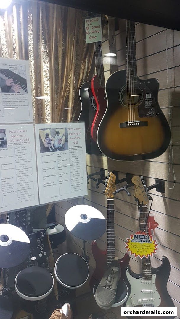 Guitars, drum pads, and music class information displayed in a shop window.