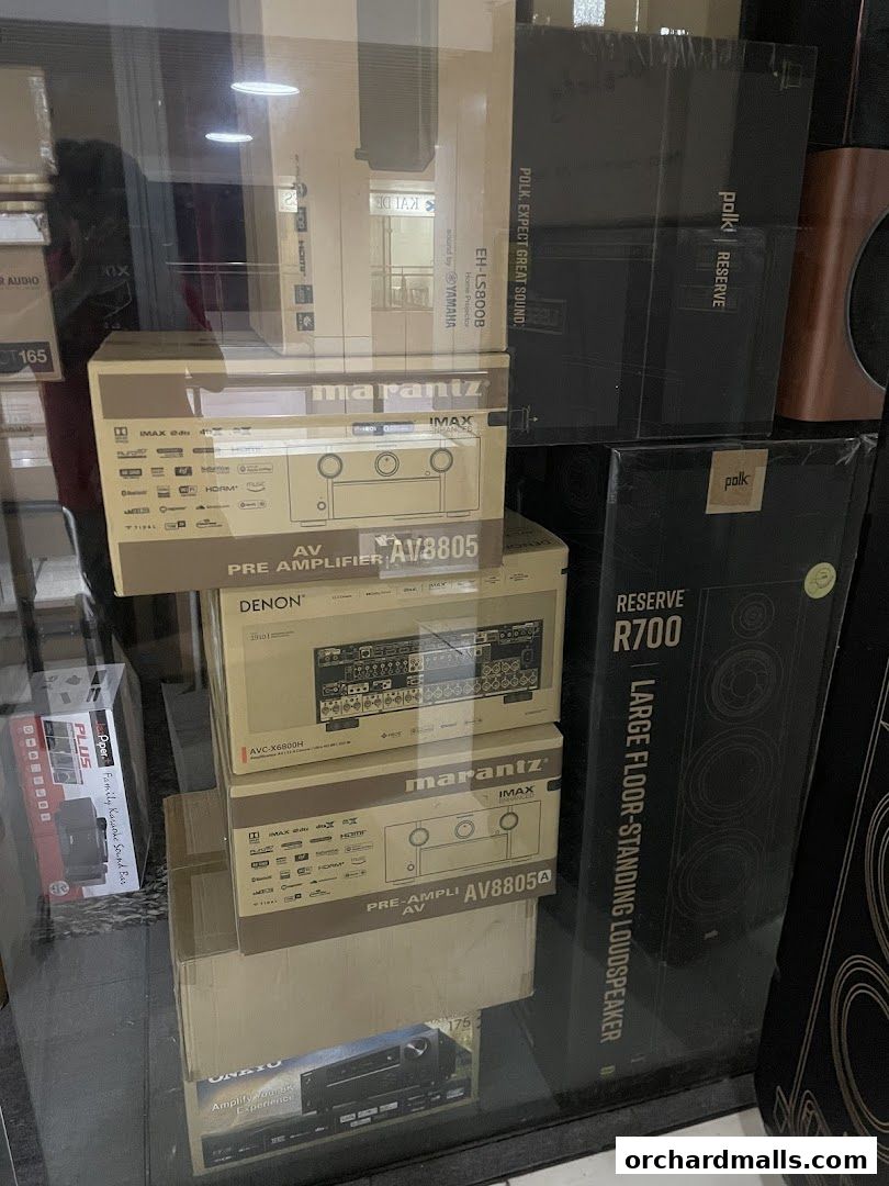 Boxes of audio equipment, including amplifiers and speakers, are stacked inside a shop window.