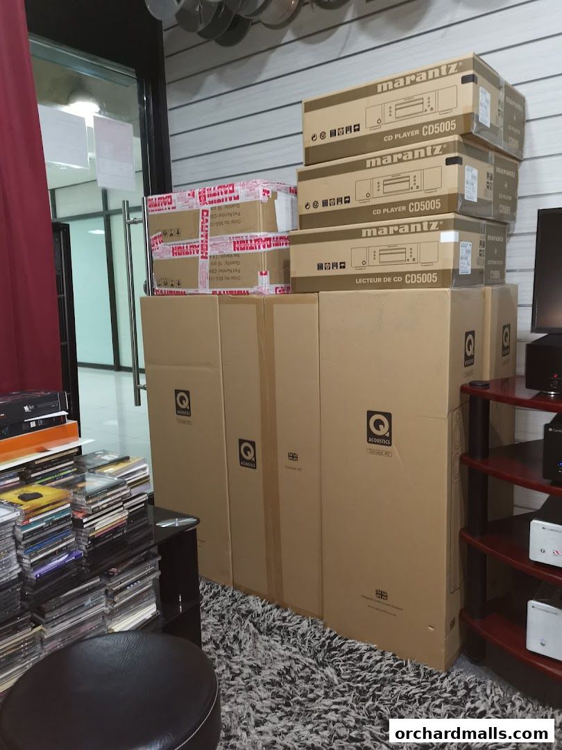 Boxes of Marantz CD players and Q Acoustics speakers stacked inside a retail store.