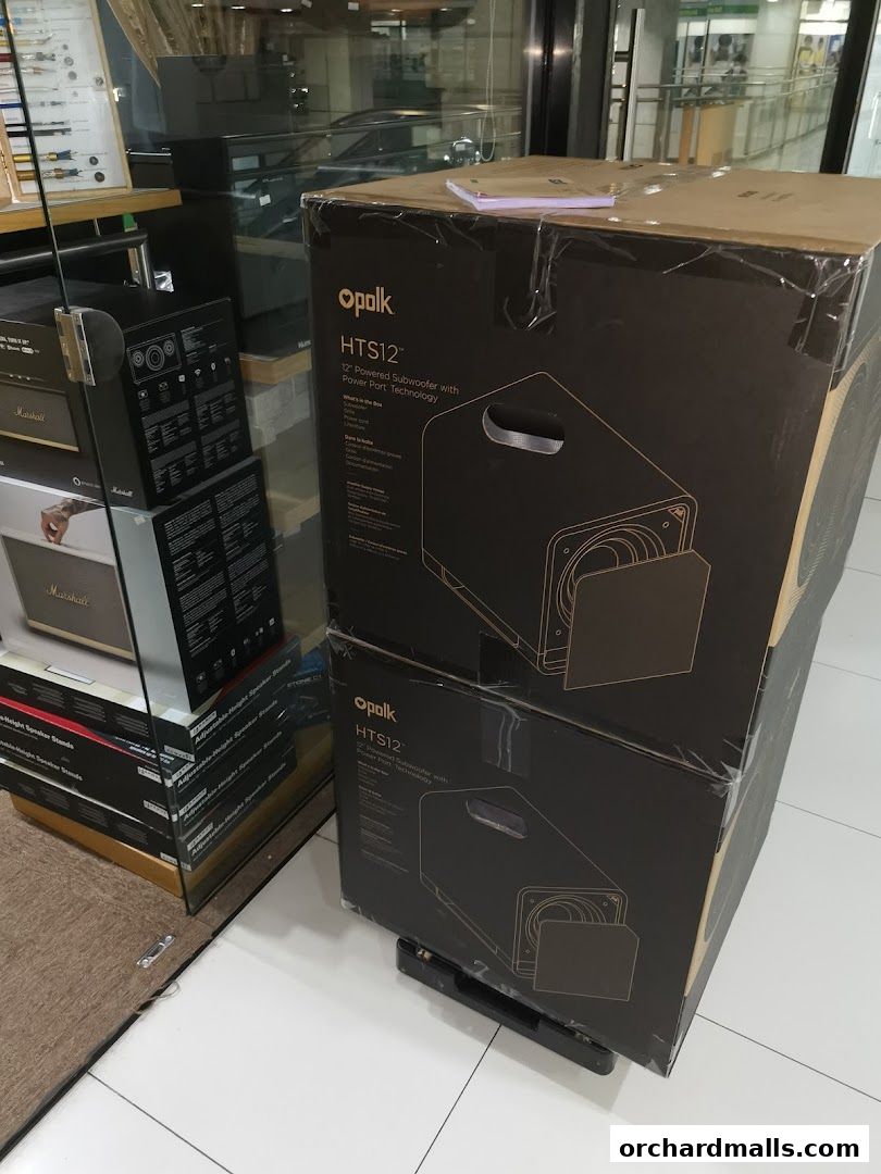 Boxes of Polk HTS12 12" Powered Subwoofers are stacked inside a retail store.