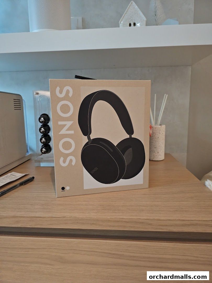 A box of Sonos headphones is displayed on a wooden surface with decorative items.