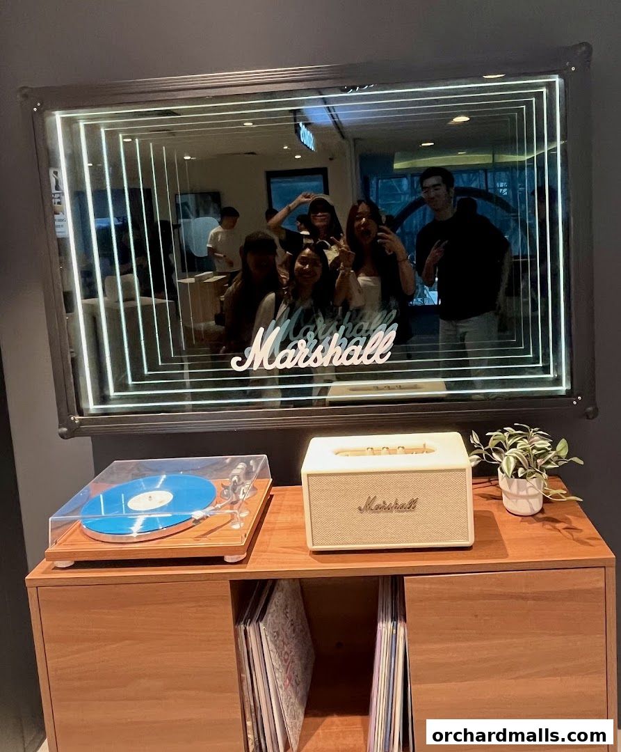 A group of friends takes a selfie in a store with a Marshall-branded infinity mirror.