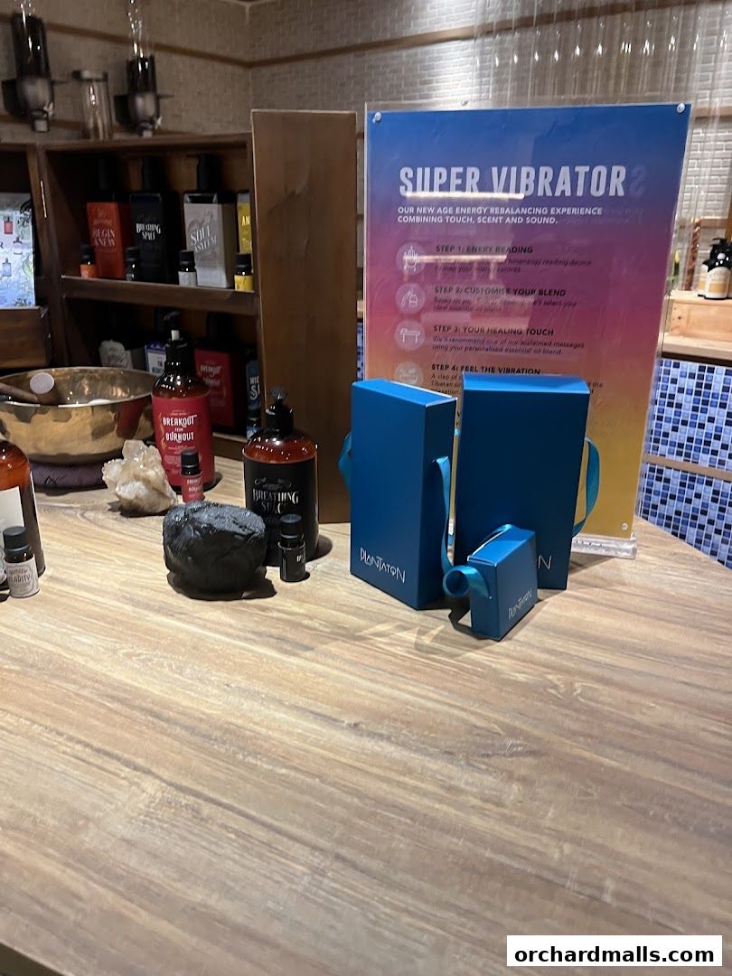 A display table with spa products, including essential oils and a 'Super Vibrator 2' promotional sign.