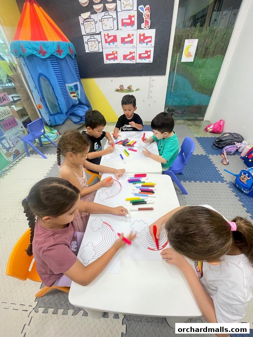 Children are coloring rainbows at tables in a classroom setting.