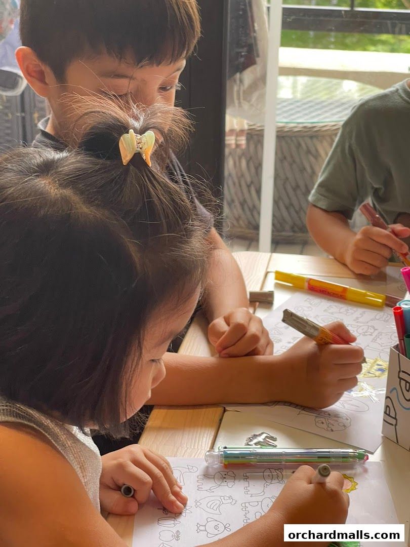 Children are focused on coloring pages with markers at a wooden table.