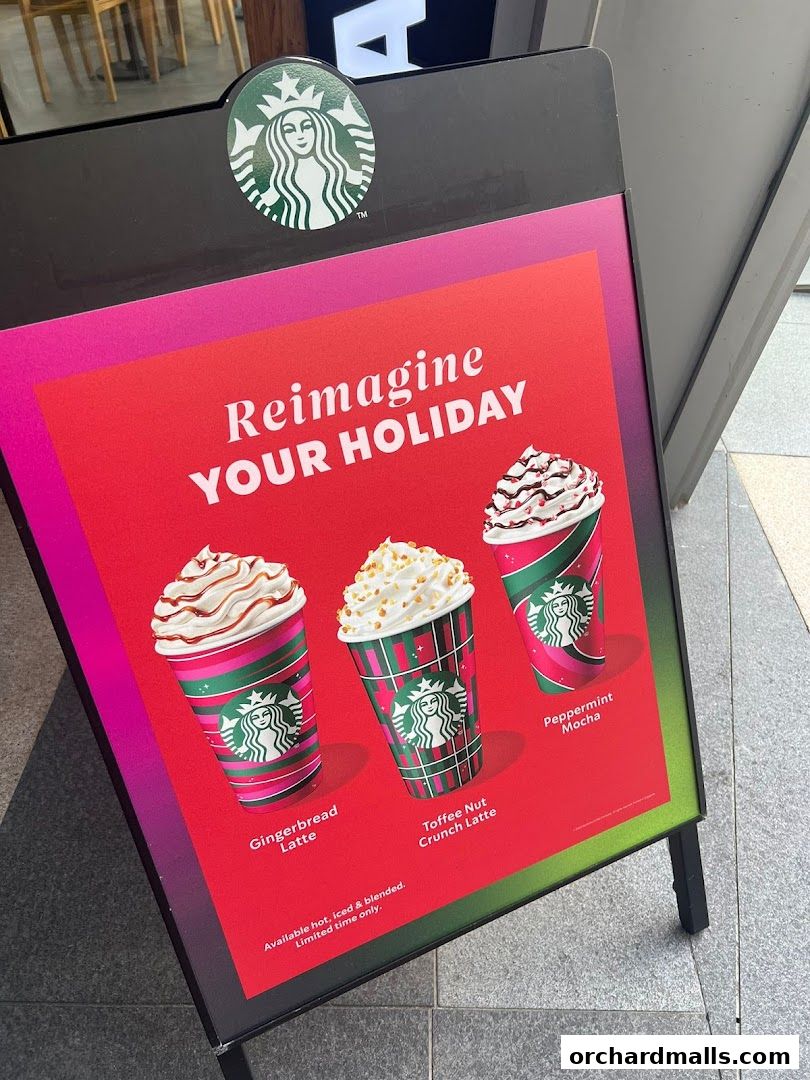 A Starbucks A-frame sign advertising holiday drinks with festive cups.