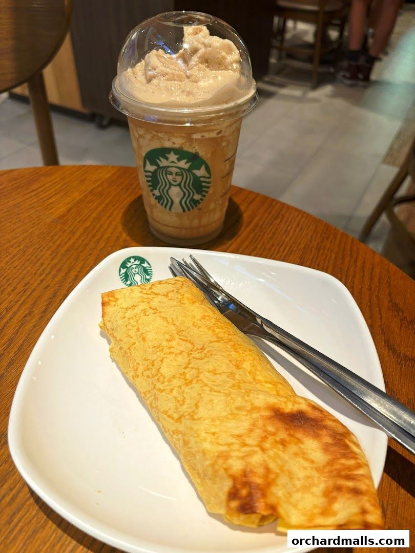 A Starbucks Frappuccino and a rolled pastry on a white plate with a fork.