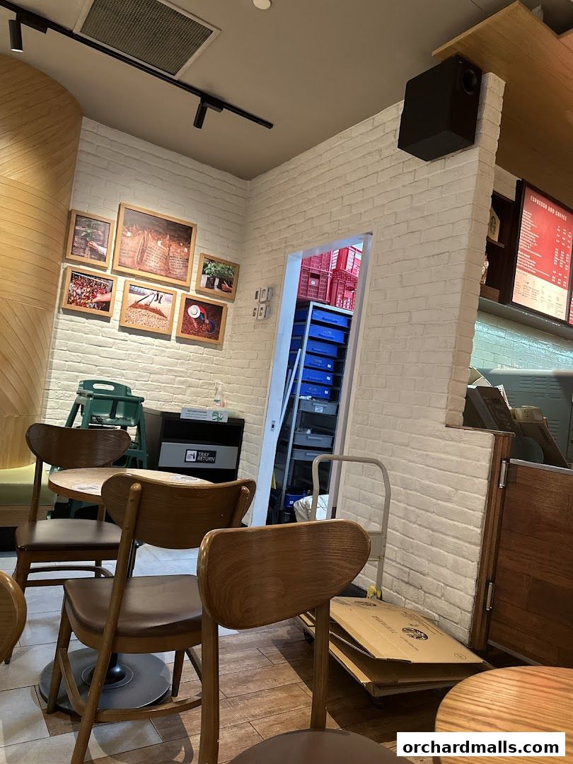 Interior view of a Starbucks cafe with seating, artwork, and a glimpse into a storage area.