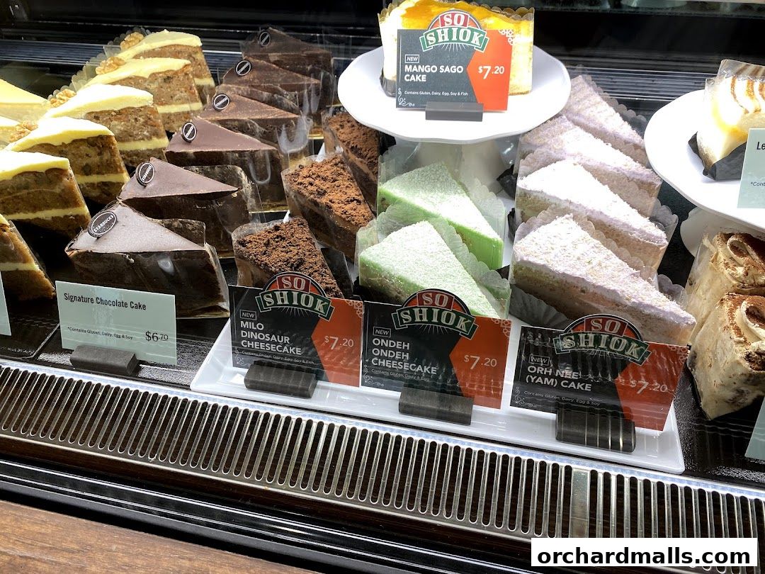 A display case filled with various slices of cakes and cheesecakes.