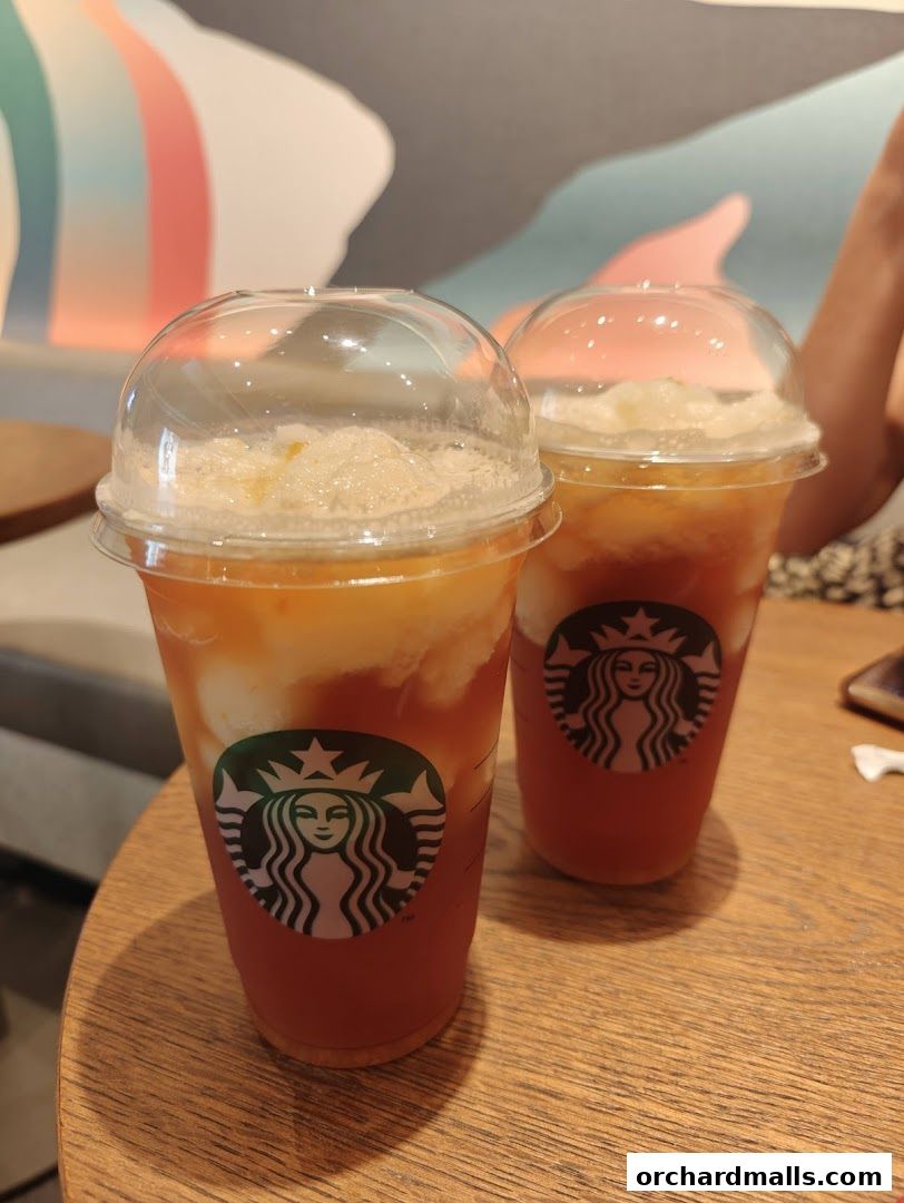 Two iced Starbucks drinks with the iconic logo on a wooden table.