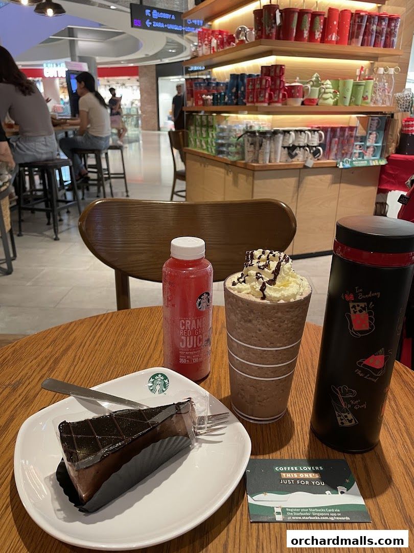 A table at Starbucks with a slice of chocolate cake, a bottle of juice, and a drink.