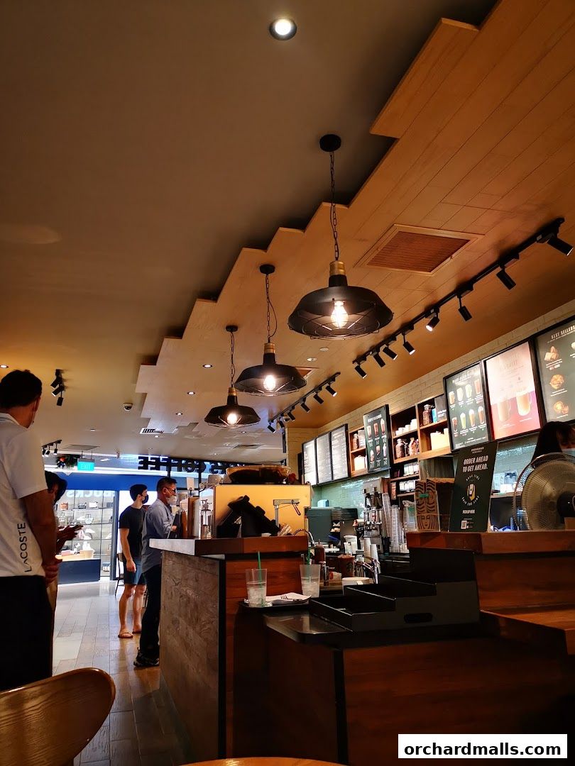 Interior view of a Starbucks coffee shop with customers at the counter and menu boards on the wall.