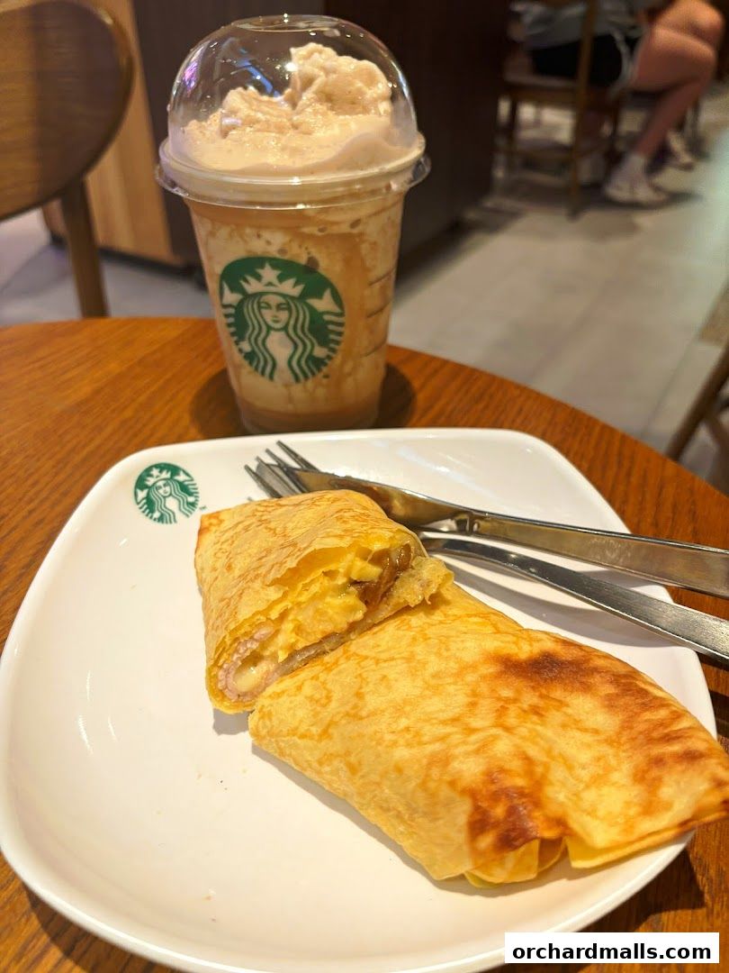 A Starbucks Frappuccino and a cut wrap on a white plate with cutlery.