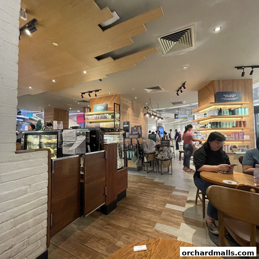 Interior view of a busy Starbucks cafe with customers and merchandise on display.