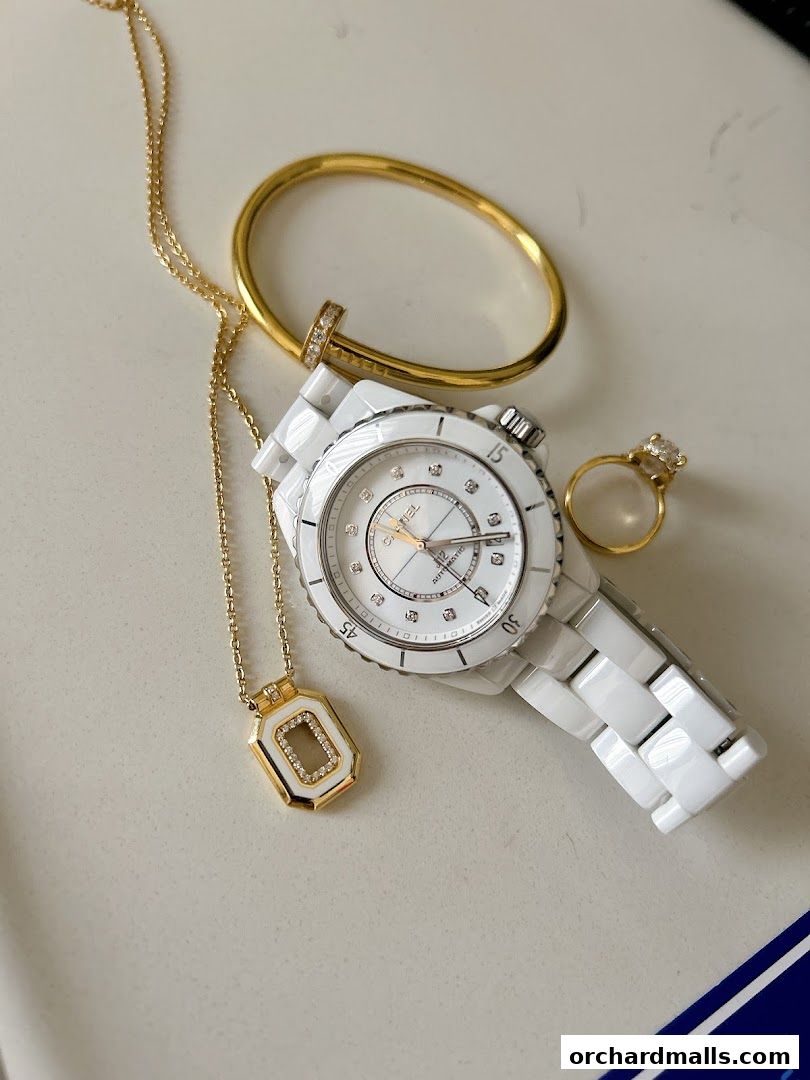A collection of luxury jewelry and a watch displayed on a white surface.