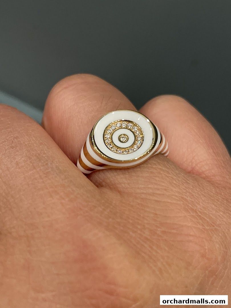 A close-up shot of a white and gold ring with diamonds on a finger.