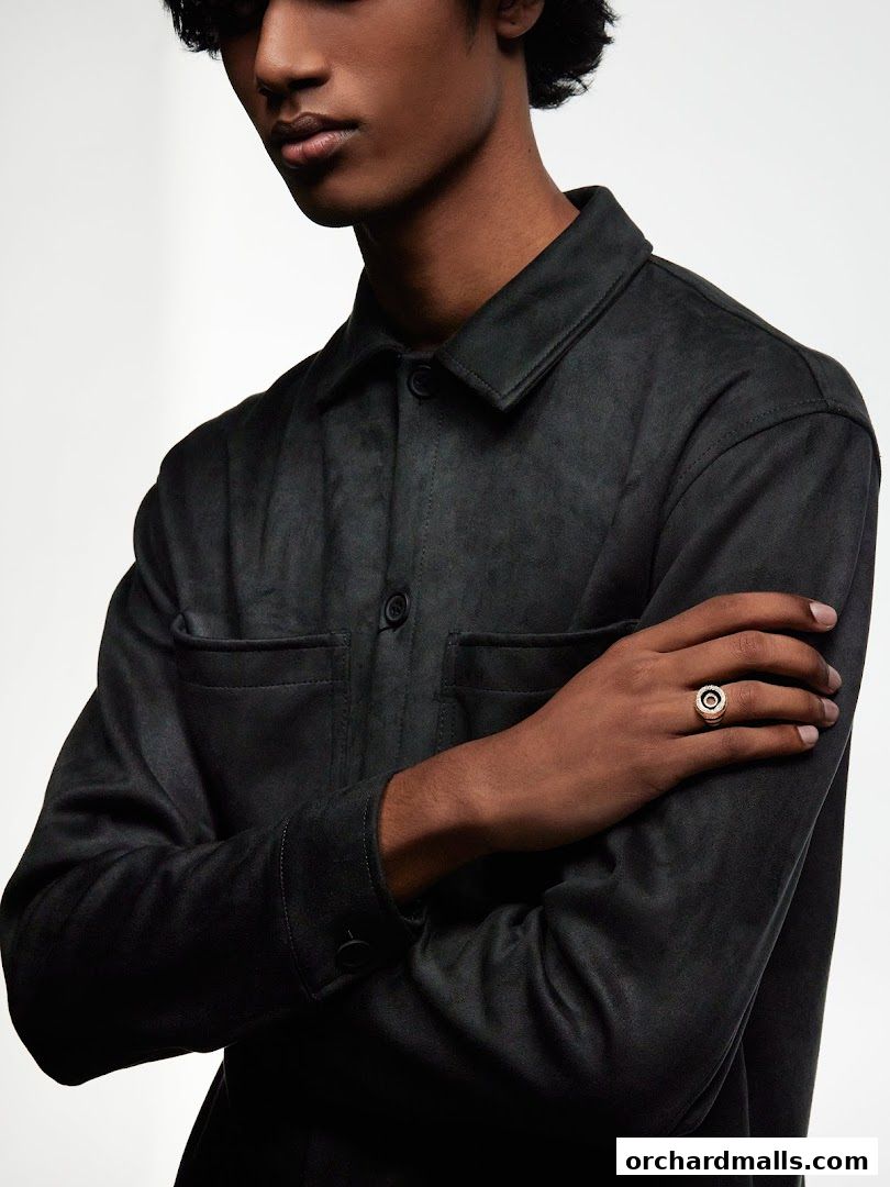 A man wearing a dark jacket and a statement ring on his finger.