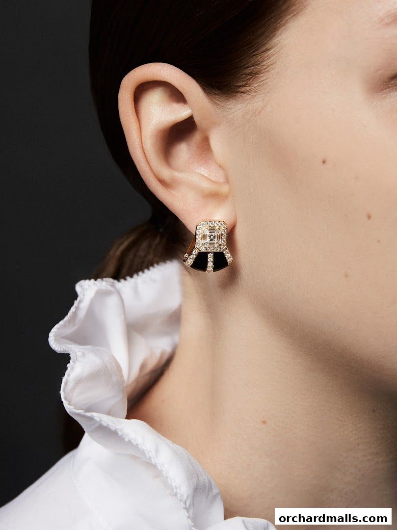 Close-up of a woman's ear adorned with an elegant diamond and black stone earring.
