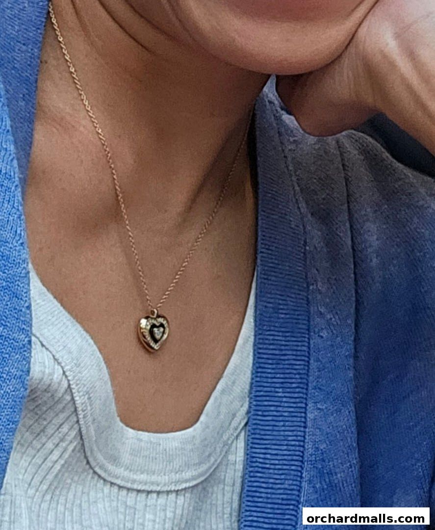A close-up of a person wearing a gold heart-shaped locket necklace.