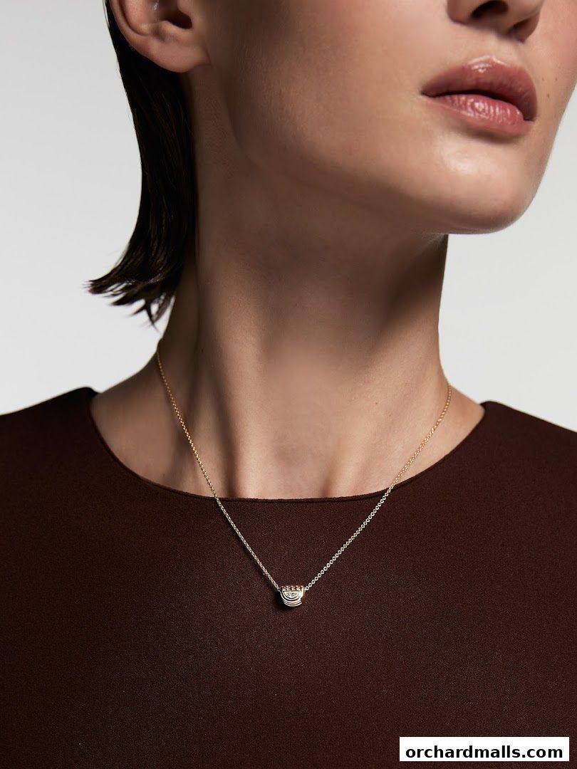 A close-up shot of a woman wearing a delicate gold necklace with a pendant.