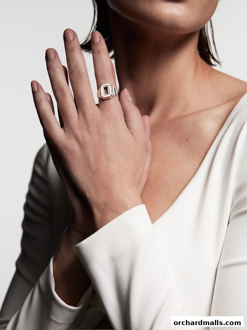 A woman's hand wearing a signet ring with a geometric design and small diamonds.