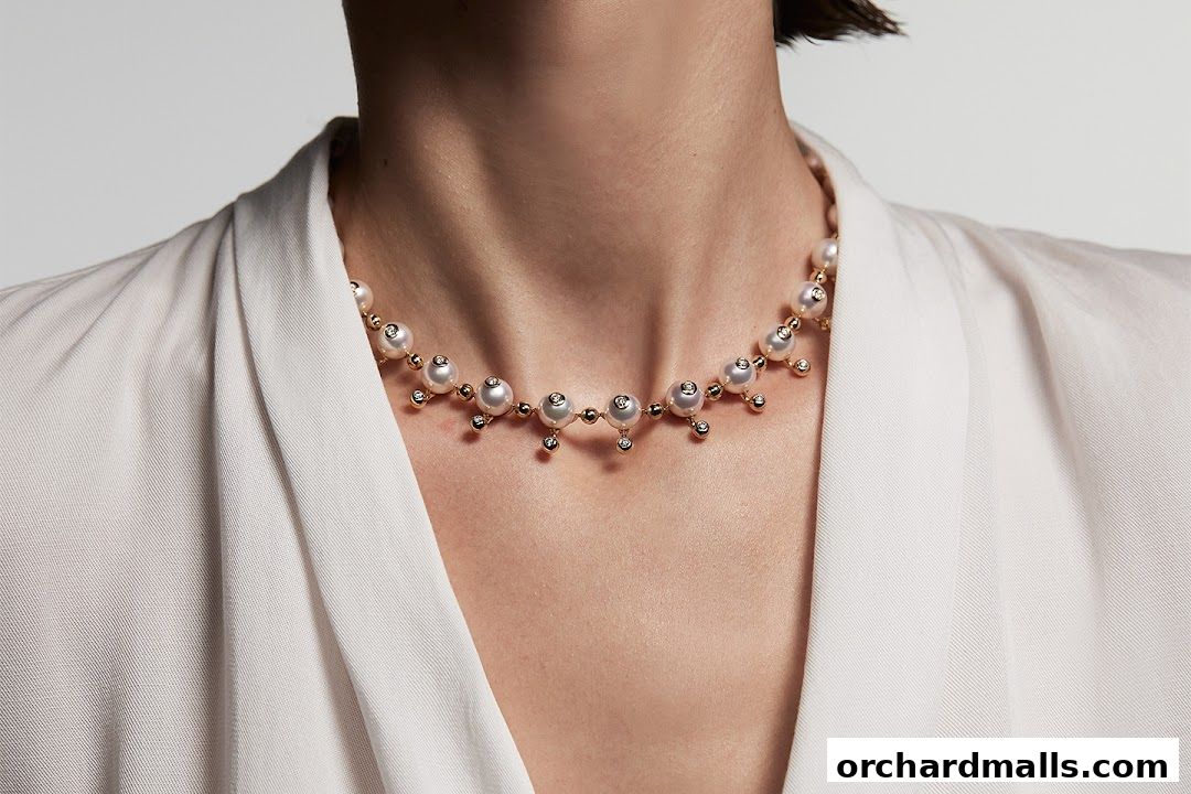 A close-up of a pearl and diamond necklace on a person wearing a white garment.