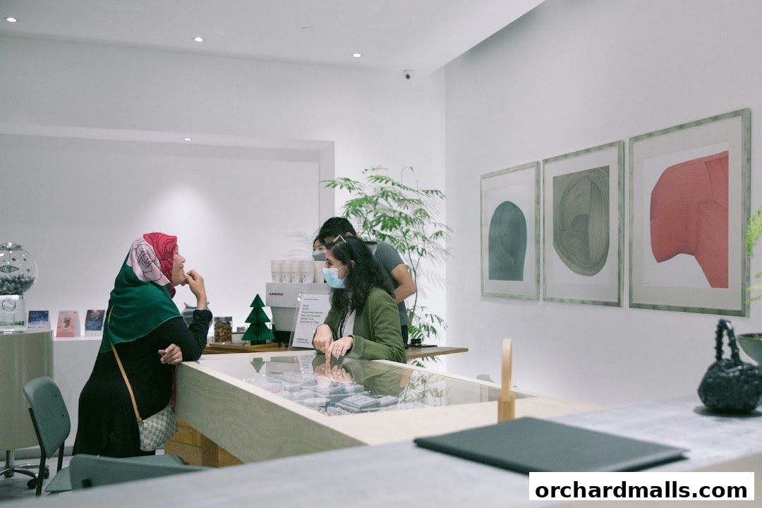 Customers interact with staff at a modern retail counter with artwork on the wall.