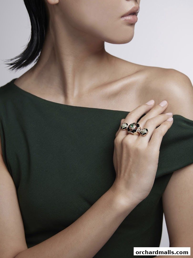 A woman wearing a dark green dress and ornate rings on her hand.