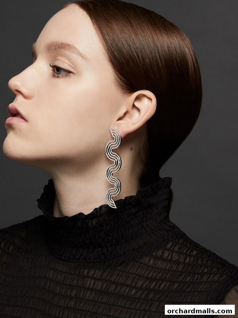 A woman models a pair of striking, wavy, diamond-encrusted earrings.