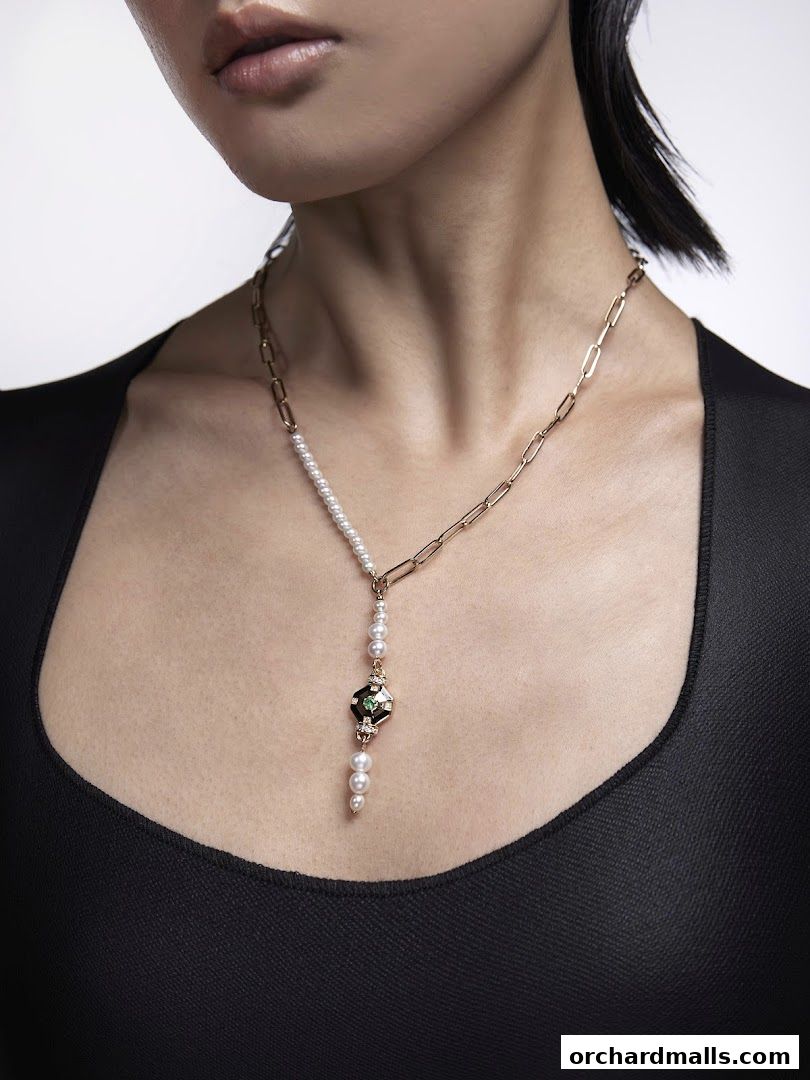A woman models a unique gold chain necklace with pearls and a decorative pendant.