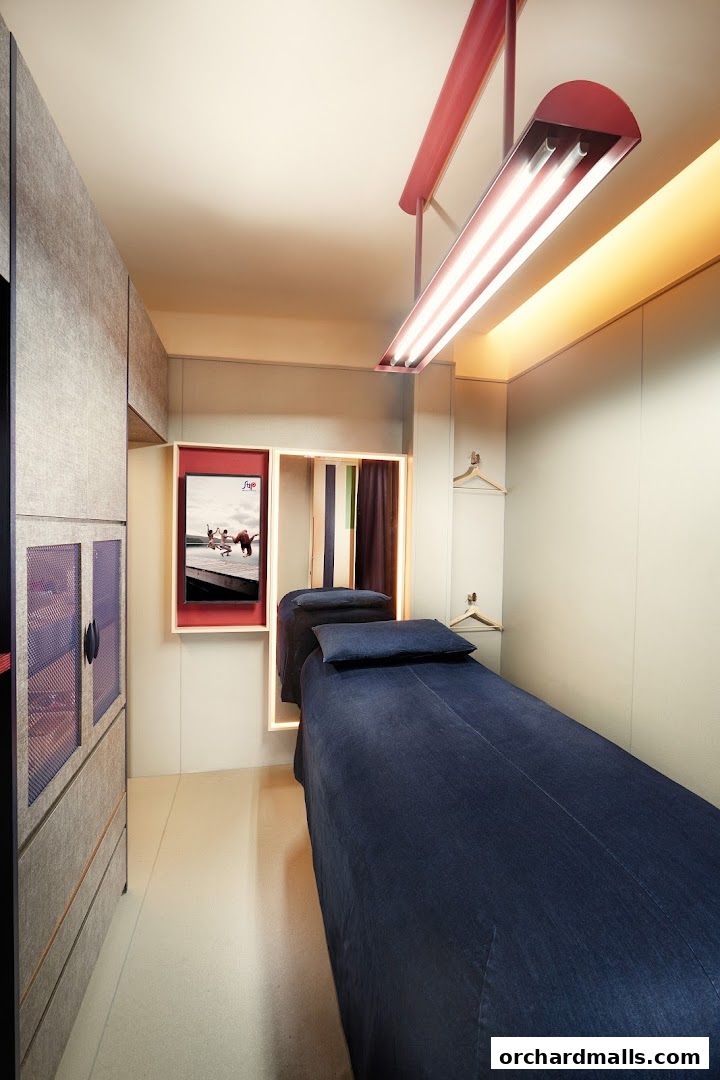 Interior of a treatment room with a massage bed, storage, and a screen displaying an advertisement.