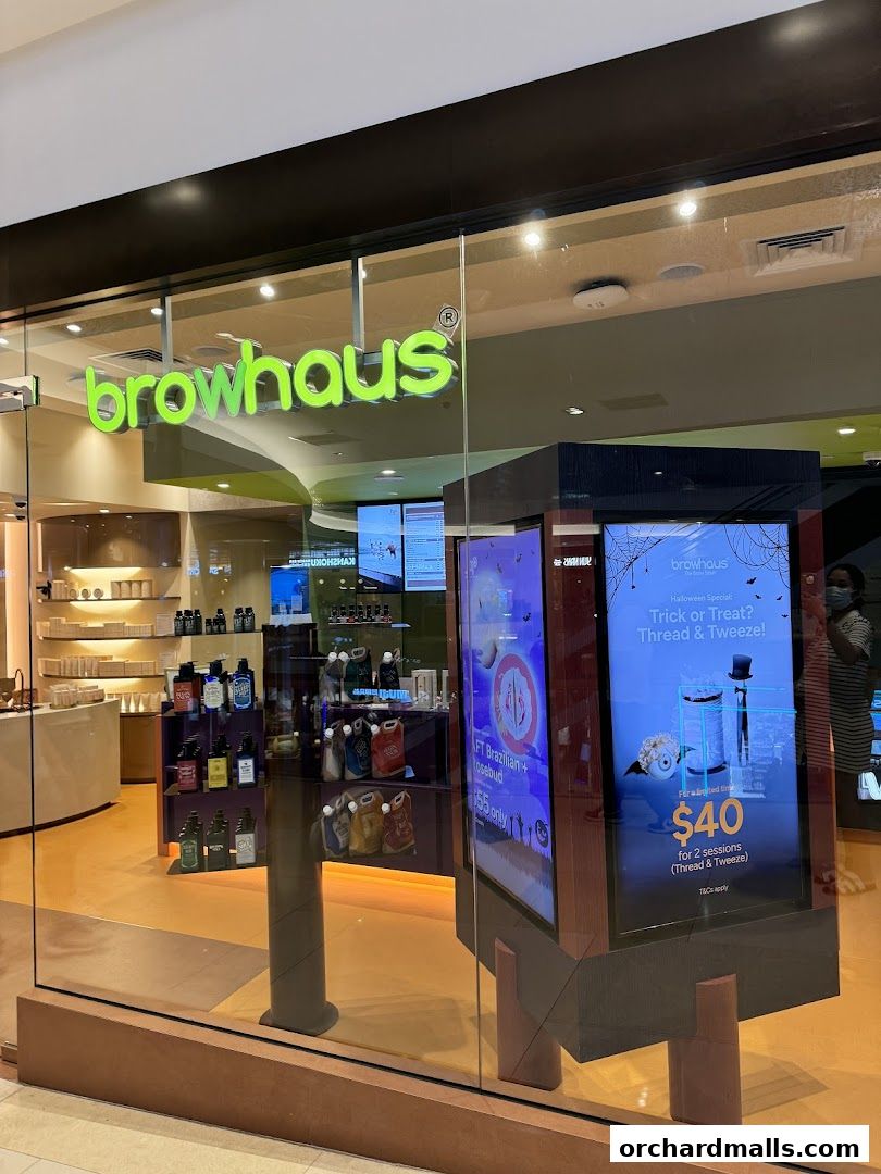 The exterior of a Browhaus shop with products displayed inside and digital advertisements.