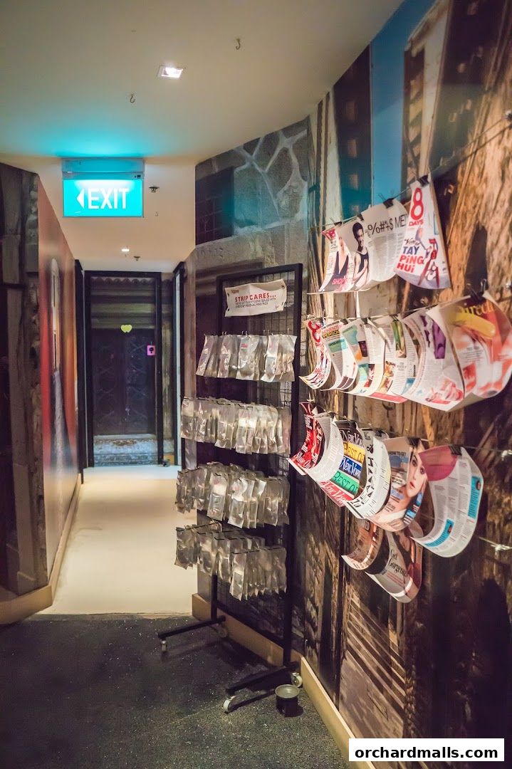 Hallway with an exit sign, display racks of products, and magazines on the wall.